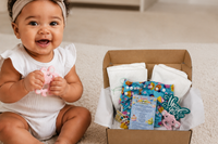 Baby playing with teething toy while sitting next the cloth diaper subscription box