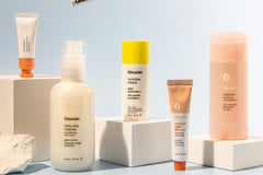 Five luxury skin care products next to each other. Some of them are standing on white blocks and the background is blue.