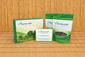 The Tea Smith tea of the month subscription box with information card and two bags of tea on a bamboo background.