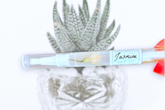 A close up of Greenmade goods Jasmine Cuticle Oil against a white background with a light green succulent.