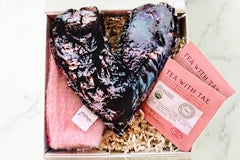 The care package box- featuring giant heart flax spearmint lavender scented hot and cold pack, hibiscus rose tea and cozy pink fuzzy socks 