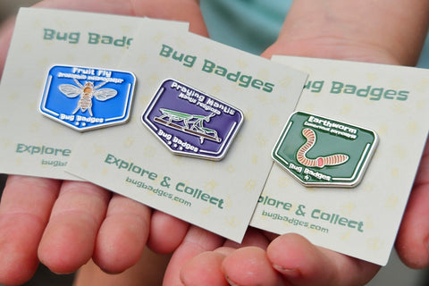 Angled photo of a Bug Badges canvas banner laid on a surface, showing “Bug Badges / Explore & Collect” and a large collection