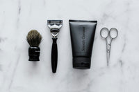 Close up high quality photo of a grooming brush, razor, smooth operator lotion and scissors for mens grooming.