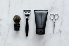Close up high quality photo of a grooming brush, razor, smooth operator lotion and scissors for mens grooming.