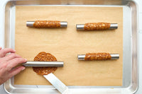 Apple Pie Brandy Snaps DIY baking kit process with hands shaping caramel lace shells around stainless-steel molds.