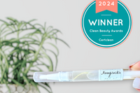 A close up of Greenmade goods Honeysuckle Cuticle Oil, a Clean Beauty Winner badge in the upper right corner against a light background