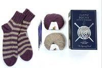 Learn to Knit sock kit with finished socks, double-pointed needles, and 2 balls of alpaca yarn in flatlay arrangement