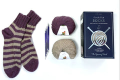 Learn to Knit sock kit with finished socks, double-pointed needles, and 2 balls of alpaca yarn in flatlay arrangement