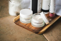 Skin care and body care products placed on a wooden tray that is on a wooden table. There is almost no background.