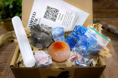 enhanted crystal subscription box, open box, showing several crystals and a card in the background, packaged with recycled materials