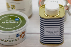 McEvoy Ranch extra virgin olive oil tin beside a tub of La Saison almonds and a jar of McEvoy Ranch Chardonnay mustard