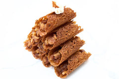 Apple Pie Brandy Snaps DIY baking kit result with 28 filled lace desserts arranged in four neat rows on a white tray.