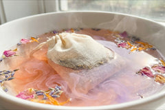 Magnesium bath soak sachet releasing peachy pink color from Alaea salt and lavender botanicals in water