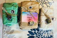 tarot and Oracle decks wrapped in tissue and brown paper surrounded by unwrapped tarot and oracle decks and crystals 