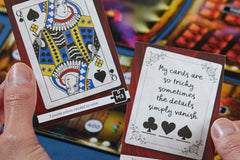 A person holding 2 cards that are from a mystery thrilling escape game and a board deck in the background.