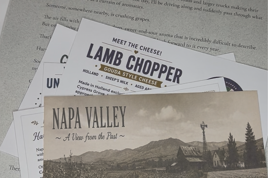 Close-up of some of the printed collection, showing the September harvest letter, Lamb Chopper cheese information card, and vintage postcard