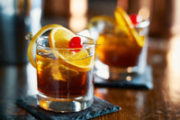 Classic Old Fashioned cocktail with an orange peel garnish, luxury cherries, and a crystal-clear ice