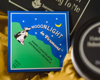 Introverts Retreat box closeup of a dark chocolate espresso crunch chocolate bar. A candle is also visible on the side.