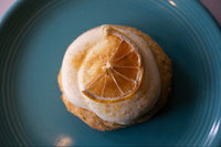 A delicious lemon cookie with lemon cheesecake frosting with a freeze dried lemon slice on a blue plate