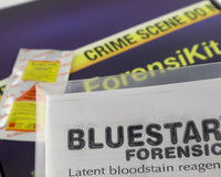 A blue box containing a forensikit is displayed in the back while blood detecting luminol is in the foreground