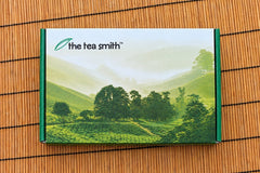 Image of the tea of the month box closed with tea field image across the box with the Tea Smith logo on a bamboo background.