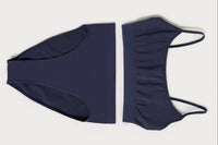 A flat lay of a navy blue scoop bralette and a matching pair of high waisted briefs, on top of a white background