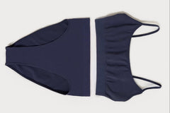 A flat lay of a navy blue scoop bralette and a matching pair of high waisted briefs, on top of a white background