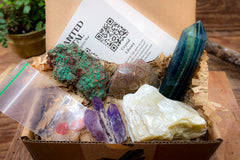 enhanted crystal subscription box, open box, showing several crystals and a card in the background, packaged with recycled materials