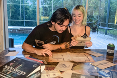 A couple on a date night sitting at a table solving a murder mystery game from The Deadbolt Mystery Society.