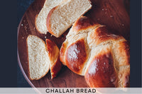 Challah bread on brown cutting board cut into pieces