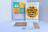 The Wealth Money Can’t Buy by Robin Sharma surrounded by bookmarks, a thank-you card, and a branded mailer.