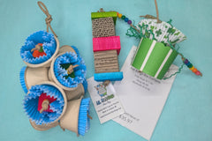 A variety of bird toys laid out on a blue cloth. Next to it is an itemized receipt and a business card. 
