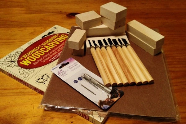 A book on woodcrafting alongside wooden blocks, brushes and other crafting supplies