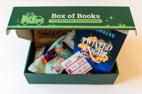 Inside the Box of Books subscription box, a novel titled "Twisted Knight" and bookish goodies are visible