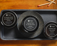 Introverts Read & Relax box contents - three different candles in black tins on a black tray on a wood table.
