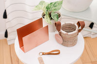 A metal mail holder from India, stamped leather "Home Sweet Home" keychain from Thailand, + a pine needle basket from Honduras.