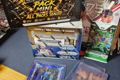 The G.O.A.T Pack Mini sealed multi-sport trading card mystery box displayed with basketball, baseball and football card packs, hobby boxes a