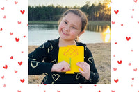 Happy child with February Activity Box. February Valentine's box with 20 OT activities, crafts, sensory materials, and fine motor tools for 