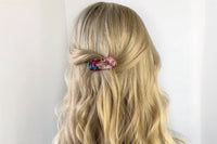 a multicolor barette shown in a casual twisted half up hairstyle on blonde hair as an example of the barettes 
