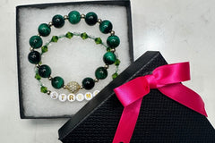 Handmade encouragement bracelet with rich green stone beads, clear and green faux crystal accents, and white letter beads spelling “STRONG” 
