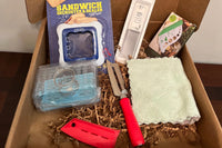 A subscription box full of different kitchen gadgets that are used for cooking, meal prep, or clean up.