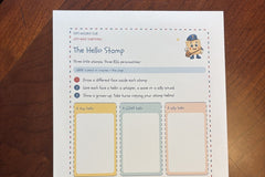 The Hello Stamp activity page from Zip's Mailbox Club on a wood table, with three blank stamps for a child to draw faces in.