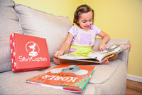 An enthusiastic girl sits cross-legged on the floor, deeply engaged in reading one of our Australia-themed picture books from the month