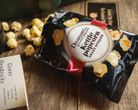 Introverts Retreat box with a bag of kettlecorn open on a wooden table. A candle sits close by the bag.