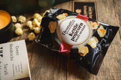 Introverts Retreat box with a bag of kettlecorn open on a wooden table. A candle sits close by the bag.