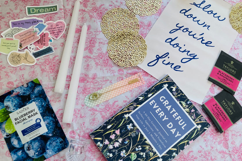 Carefully arranged slow living subscription box contents featured like self-care products, book, cozy home decor, and seasonal accessories