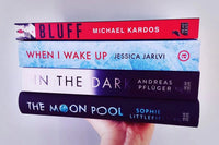 Brown box filled with a diverse collection of books in multiple genres, including crime thrillers, romance, and fantasy