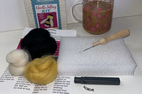 THe bee brooch crafting kit with everything include d to make this.  Also a cup of tea beside the kit.