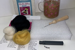 THe bee brooch crafting kit with everything include d to make this.  Also a cup of tea beside the kit.