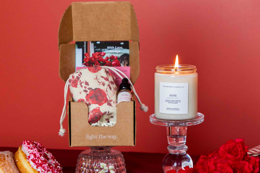 A Vellabox subscription box featuring The Glow Box candle with a croissant scent, surrounded by breakfast items and fresh fruit